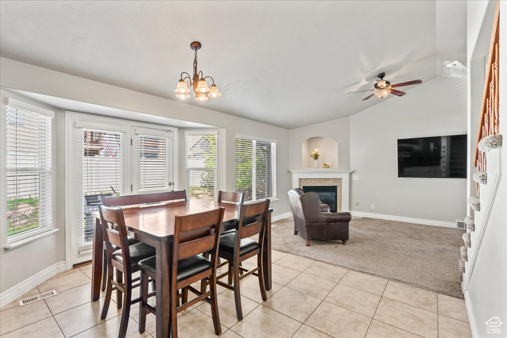 Dining room with light colored carpet, a tile fireplace, visible vents, and light tile patterned floors