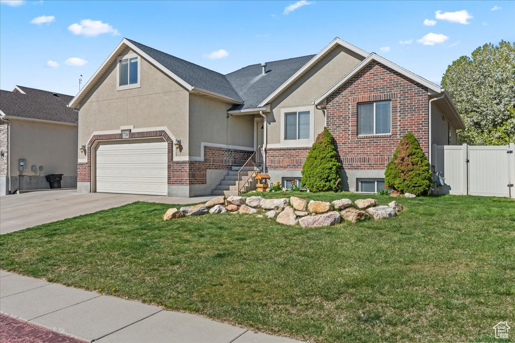 View of front of property featuring fence, a front lawn, stucco siding, concrete driveway, and a garage
