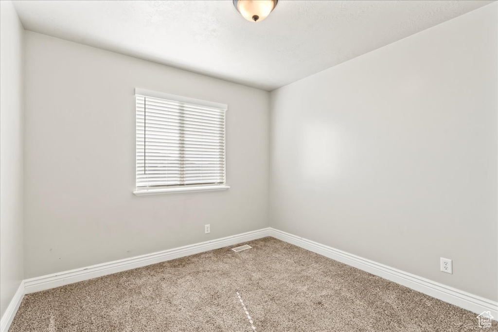 Carpeted empty room featuring visible vents and baseboards