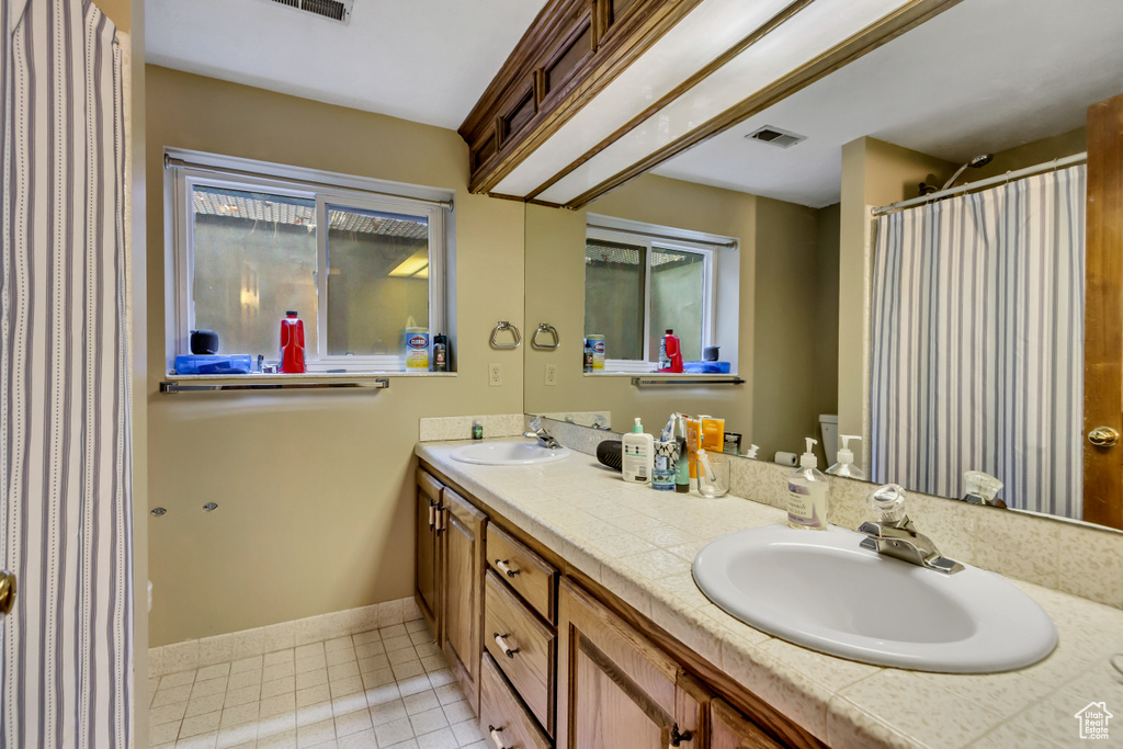 Full bathroom with tile patterned floors, visible vents, a sink, and double vanity