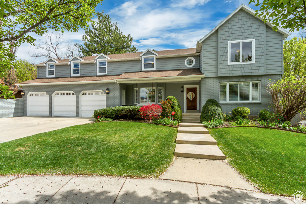 Traditional home featuring brick siding, driveway, and a front yard