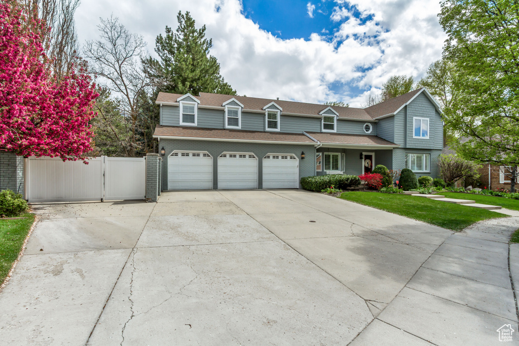 View of front of house with driveway, a front yard, fence, and roof with shingles