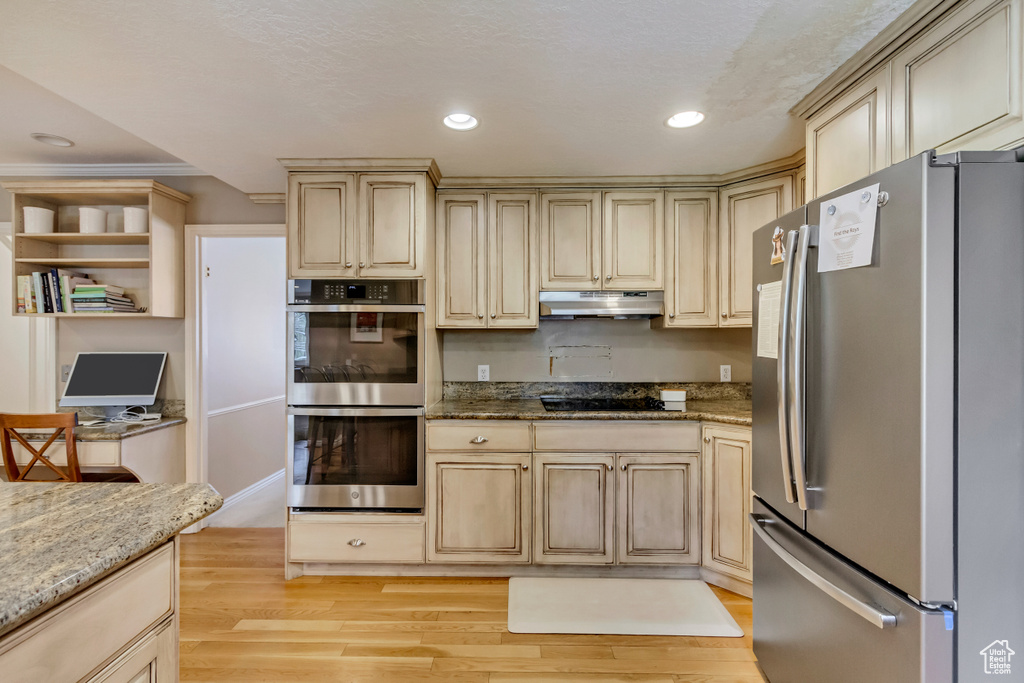 Kitchen featuring recessed lighting, light wood-style floors, light stone counters, under cabinet range hood, and appliances with stainless steel finishes