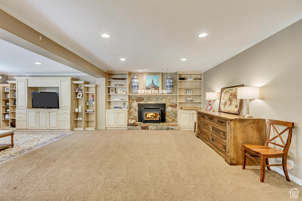 Living room with light carpet, ornamental molding, a stone fireplace, and recessed lighting