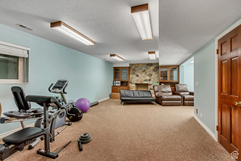 Workout area featuring carpet floors, a textured ceiling, visible vents, and baseboards