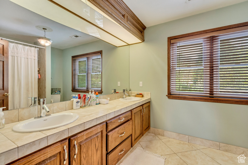 Bathroom featuring tile patterned flooring, visible vents, a sink, and double vanity