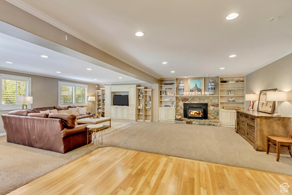Living room with wood finished floors, a fireplace, recessed lighting, and ornamental molding