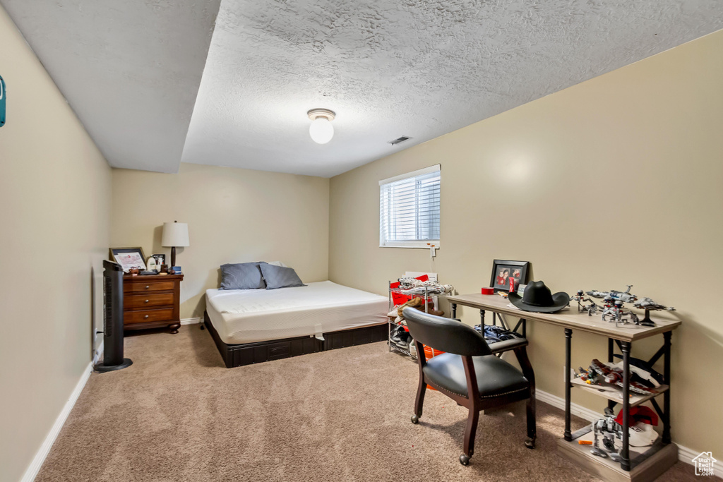 Bedroom with baseboards, a textured ceiling, and carpet
