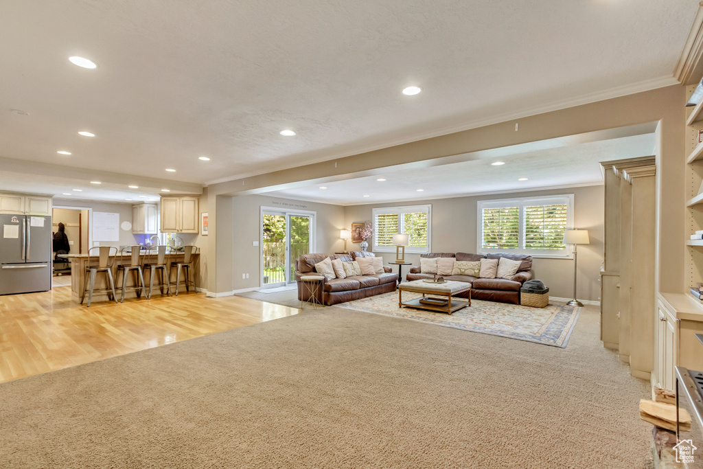 Living area with light carpet, baseboards, recessed lighting, and crown molding