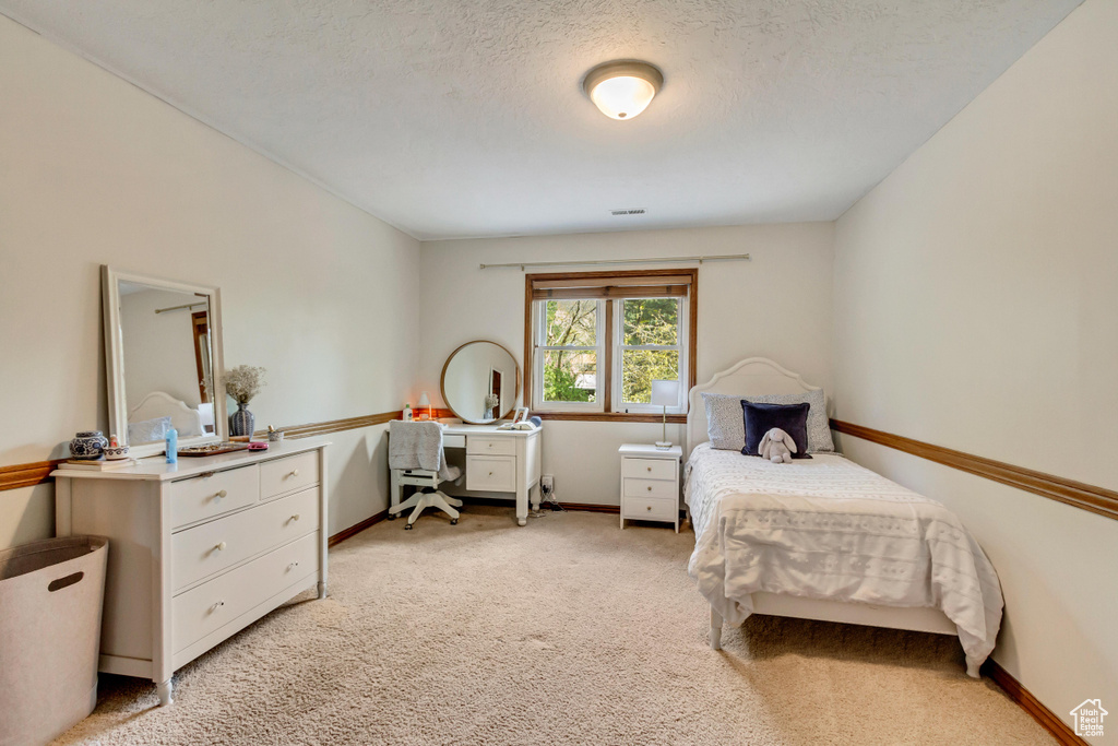 Bedroom with visible vents, baseboards, a textured ceiling, and light colored carpet