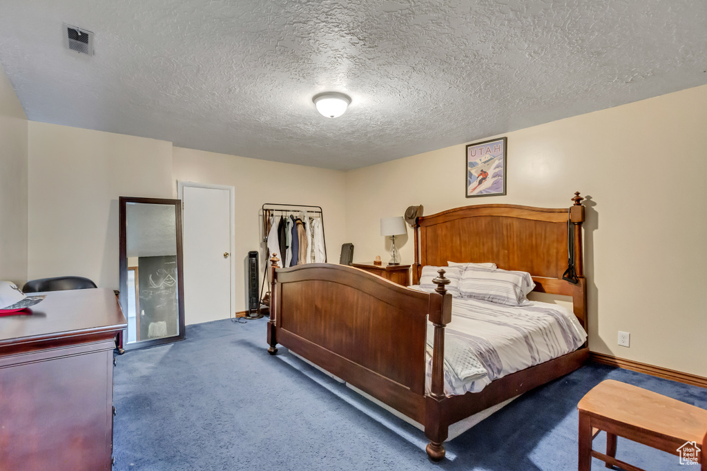 Carpeted bedroom featuring a textured ceiling, visible vents, and baseboards