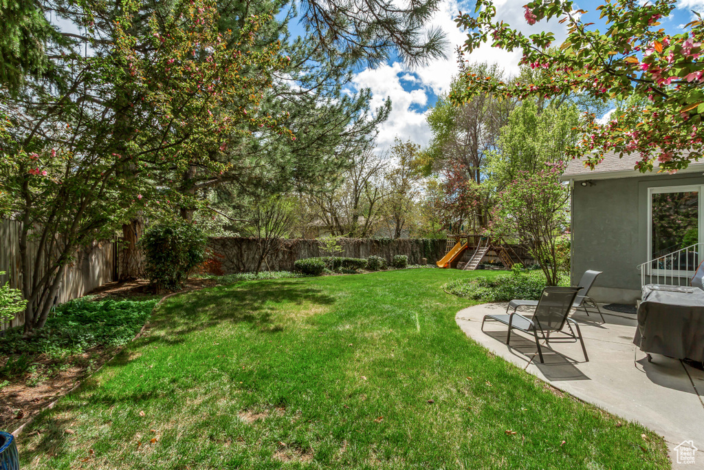 View of yard featuring a patio, a fenced backyard, and a playground