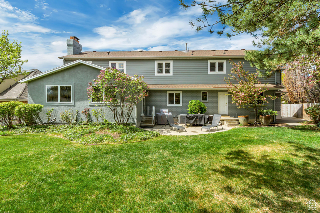 Back of property featuring entry steps, a patio area, a lawn, and fence