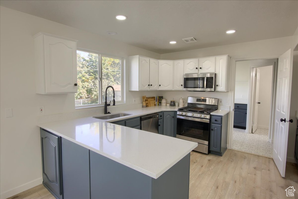 Kitchen featuring white cabinets, stainless steel appliances, a peninsula, a sink, and visible vents