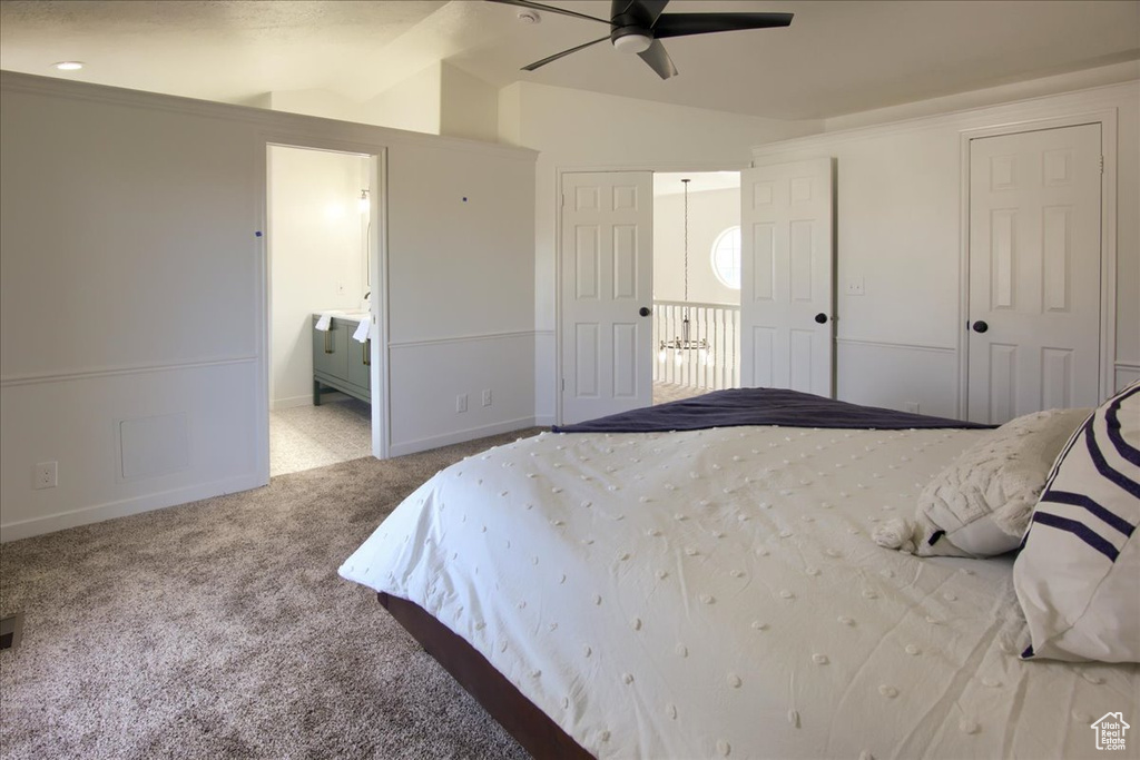 Carpeted bedroom featuring vaulted ceiling, baseboards, connected bathroom, and a ceiling fan