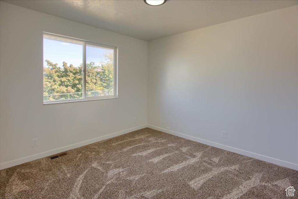Carpeted empty room featuring visible vents and baseboards
