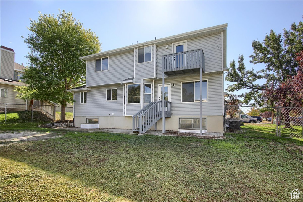 Rear view of property with fence, a lawn, and a balcony