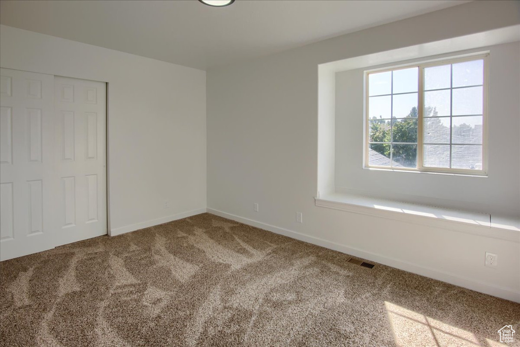 Carpeted spare room featuring baseboards and visible vents