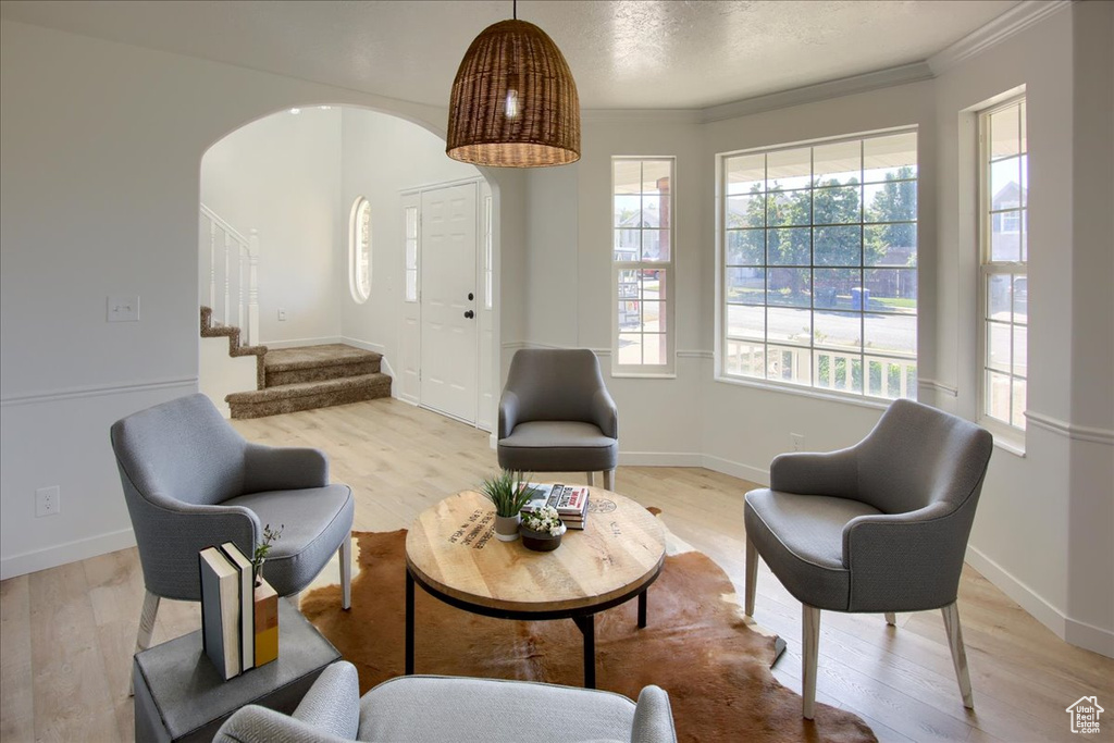 Sitting room with crown molding, stairs, arched walkways, light wood finished floors, and baseboards