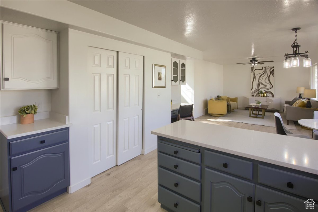 Kitchen featuring open floor plan, light wood-style floors, blue cabinetry, ceiling fan, and light countertops