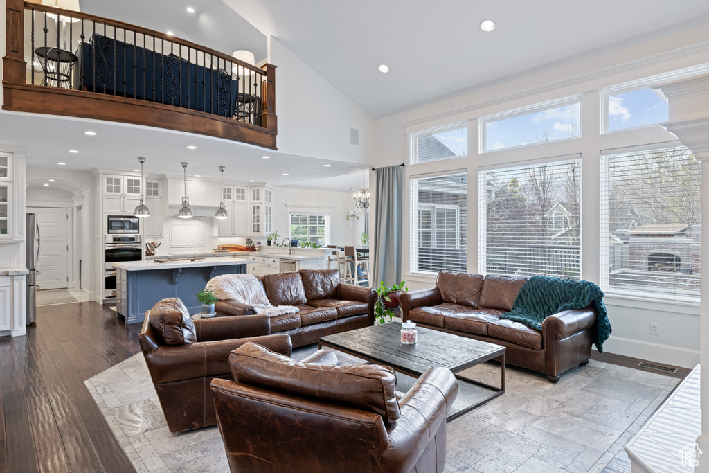 Living room with baseboards, visible vents, high vaulted ceiling, and recessed lighting