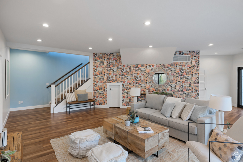 Living area featuring wood finished floors, baseboards, recessed lighting, and stairway