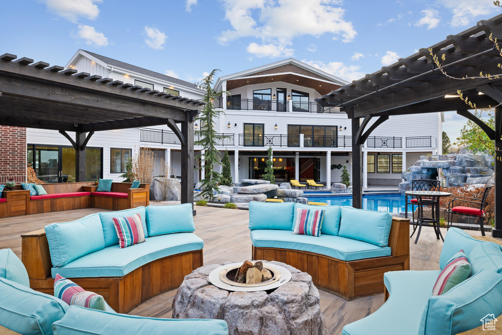 View of patio featuring a pergola, an outdoor pool, an outdoor living space with a fire pit, and a balcony