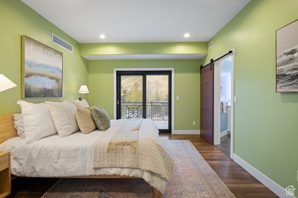 Bedroom with a barn door, visible vents, recessed lighting, wood finished floors, and access to outside