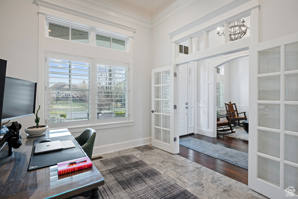 Office with a towering ceiling, french doors, arched walkways, crown molding, and baseboards