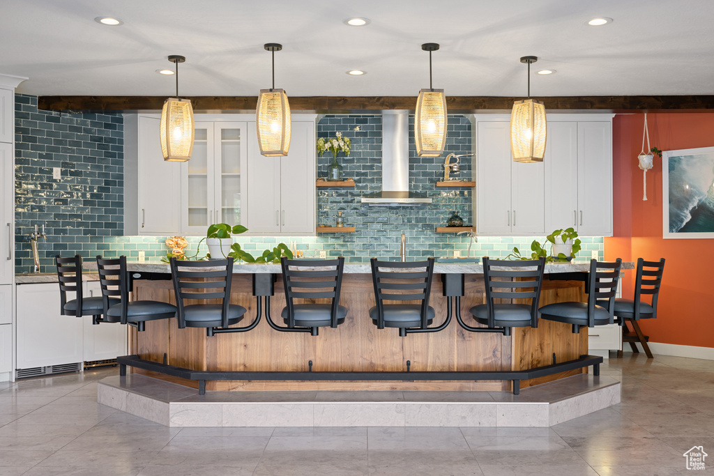 Bar featuring backsplash, wet bar, decorative light fixtures, and wall chimney range hood