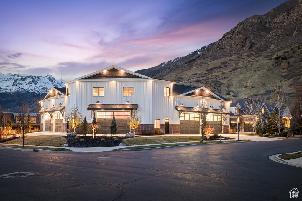 View of front of house with a mountain view, driveway, an attached garage, a balcony, and board and batten siding