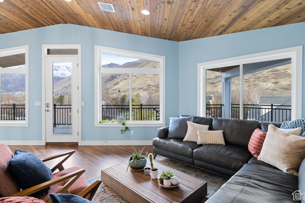 Living area with vaulted ceiling, wood finished floors, visible vents, a mountain view, and baseboards
