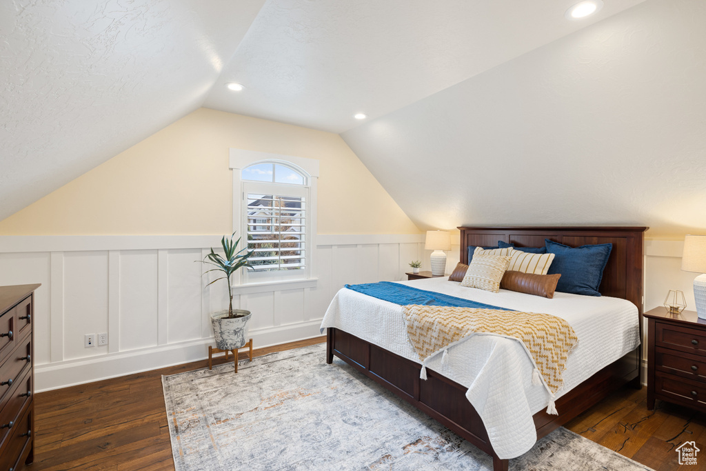 Bedroom with wainscoting, lofted ceiling, and hardwood / wood-style floors