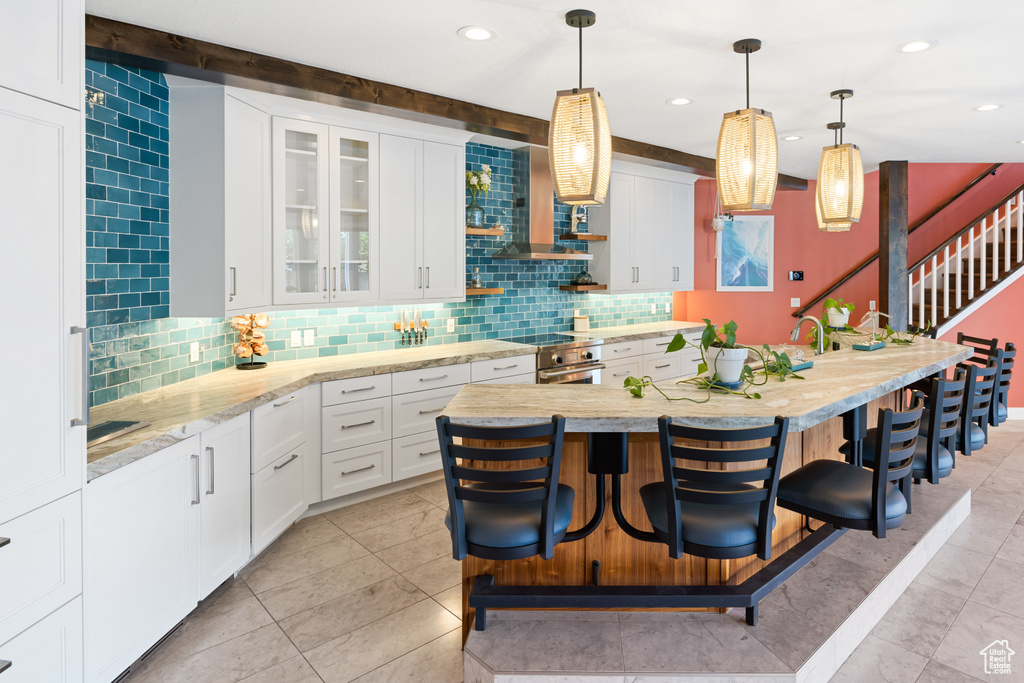 Kitchen featuring white cabinets, high end stainless steel range, tasteful backsplash, and a kitchen breakfast bar