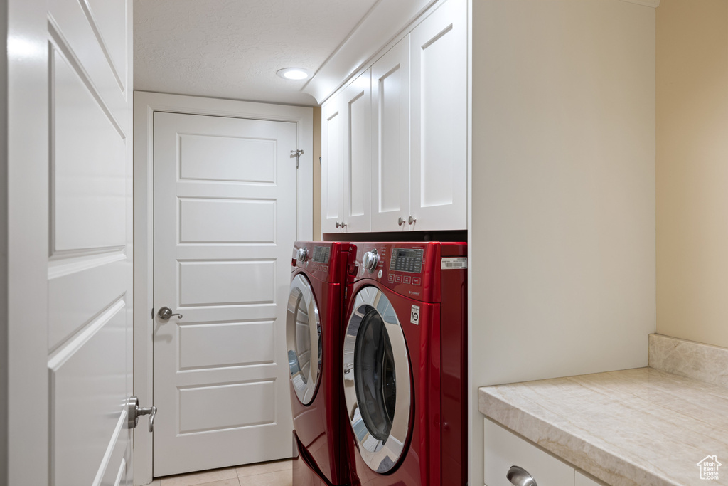 Laundry room with washing machine and clothes dryer, recessed lighting, light tile patterned floors, and cabinet space