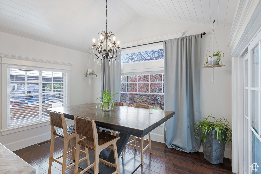 Dining space featuring a chandelier, vaulted ceiling, baseboards, and dark wood-style flooring