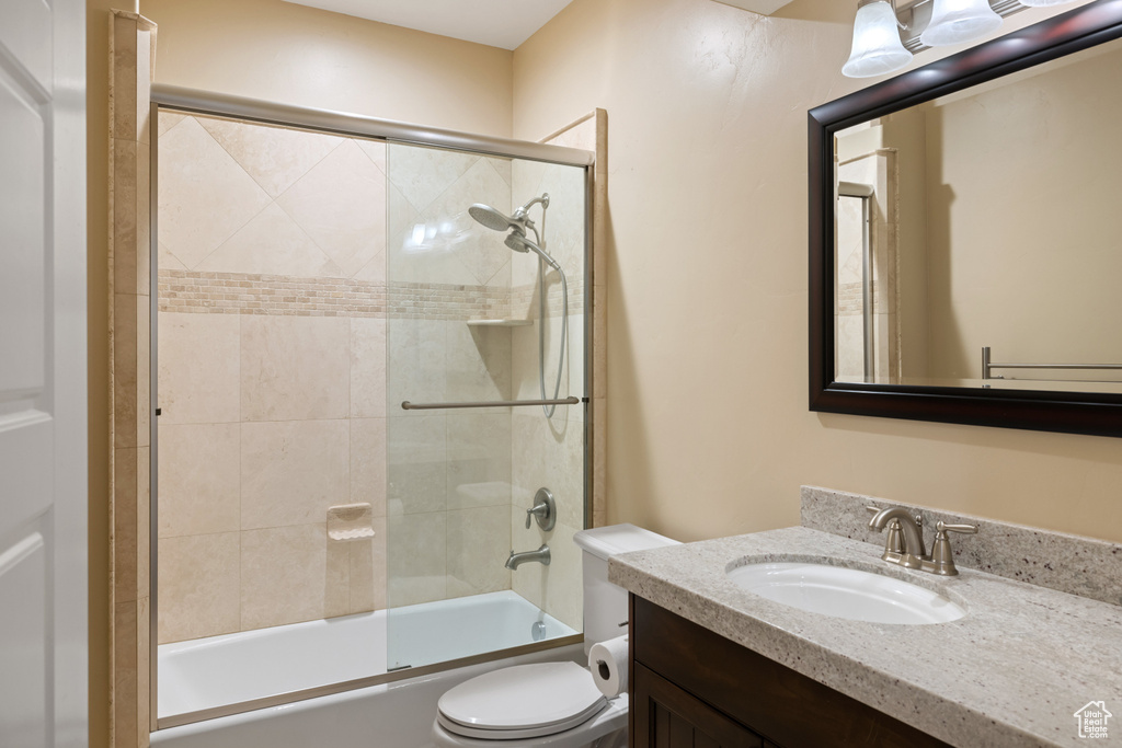 Bathroom with vanity, enclosed tub / shower combo, and toilet