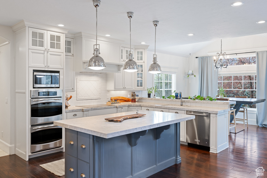 Kitchen featuring a peninsula, white cabinetry, stainless steel appliances, and a sink