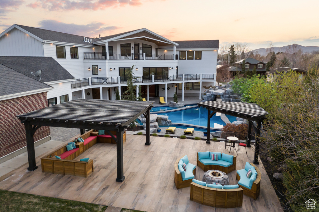 Pool at dusk featuring a gazebo, an outdoor living space with a fire pit, an outdoor pool, and a mountain view