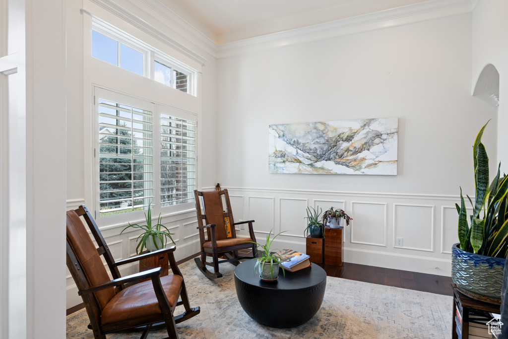 Sitting room featuring wainscoting, a healthy amount of sunlight, wood finished floors, and crown molding