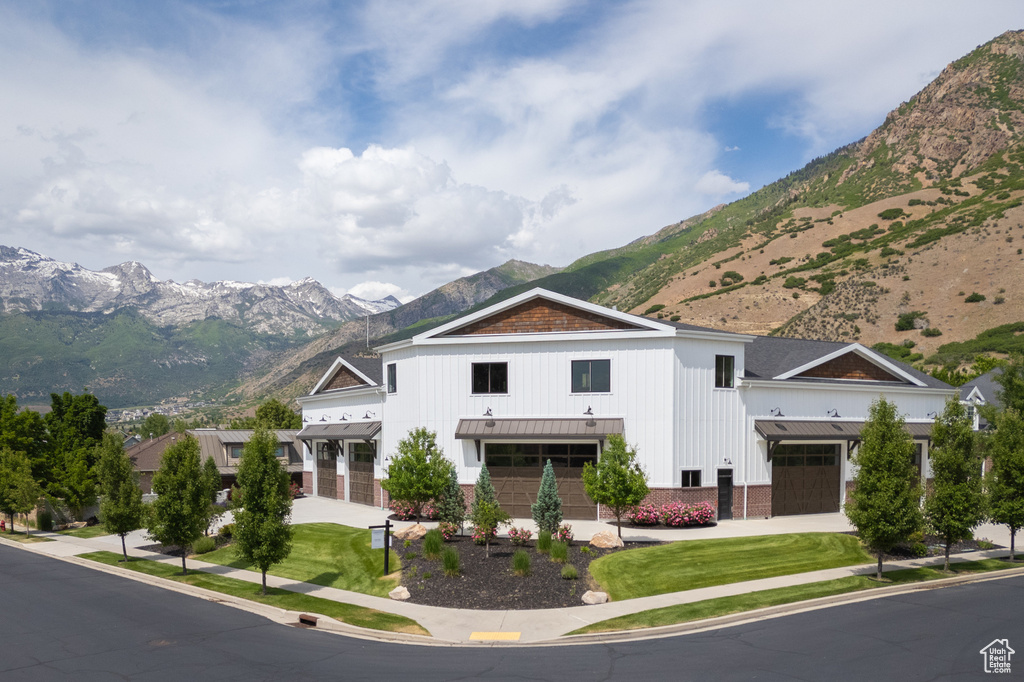 Modern farmhouse featuring a mountain view, a standing seam roof, board and batten siding, an attached garage, and metal roof