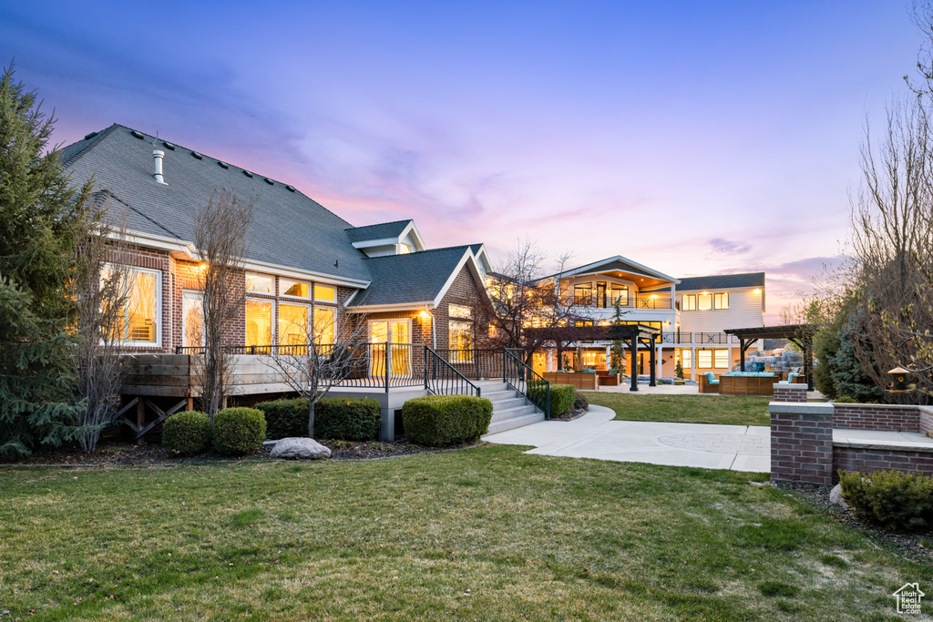 Rear view of property with a lawn, a jacuzzi, a pergola, and a patio