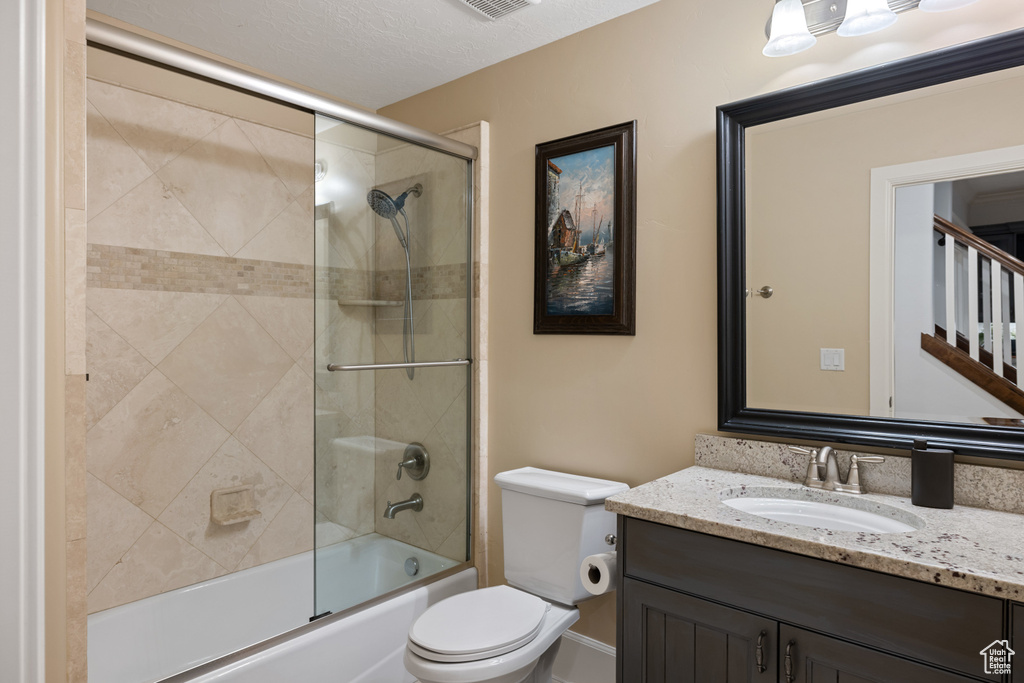 Full bathroom featuring combined bath / shower with glass door, toilet, vanity, and visible vents