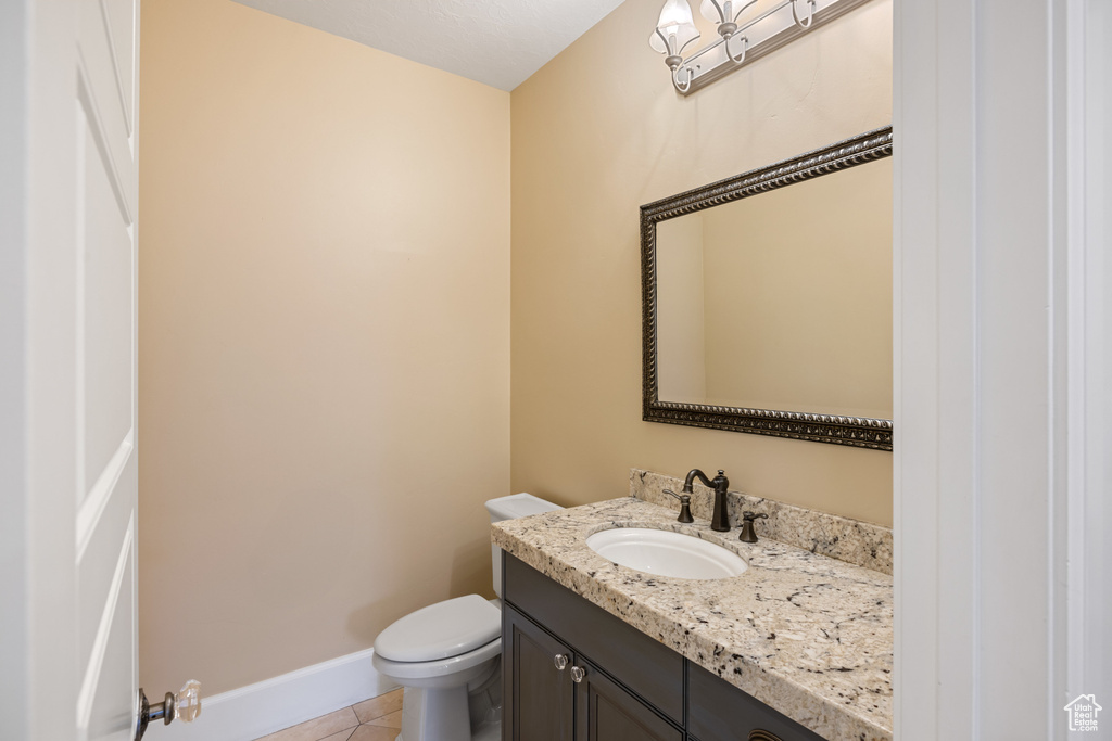 Bathroom featuring tile patterned floors, baseboards, vanity, and toilet