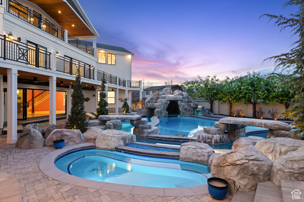 Pool at dusk with an outdoor pool and a jacuzzi