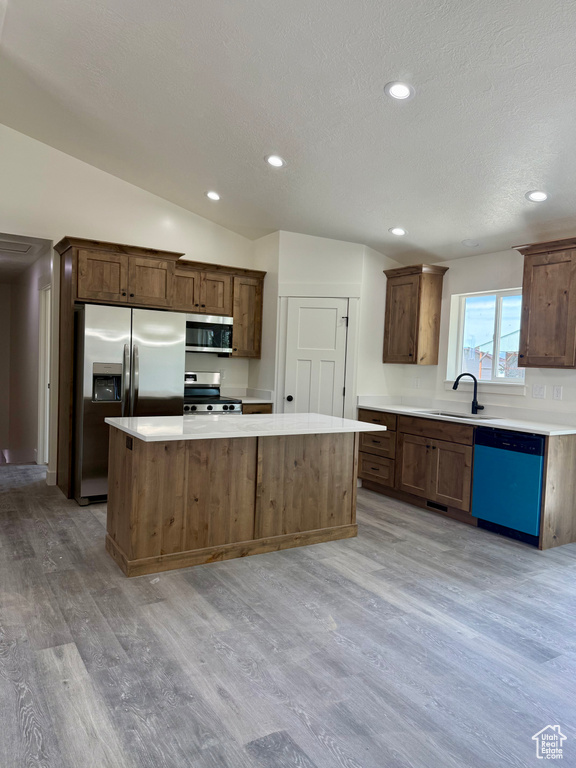 Kitchen featuring stainless steel appliances, a sink, light wood-style floors, a center island, and recessed lighting