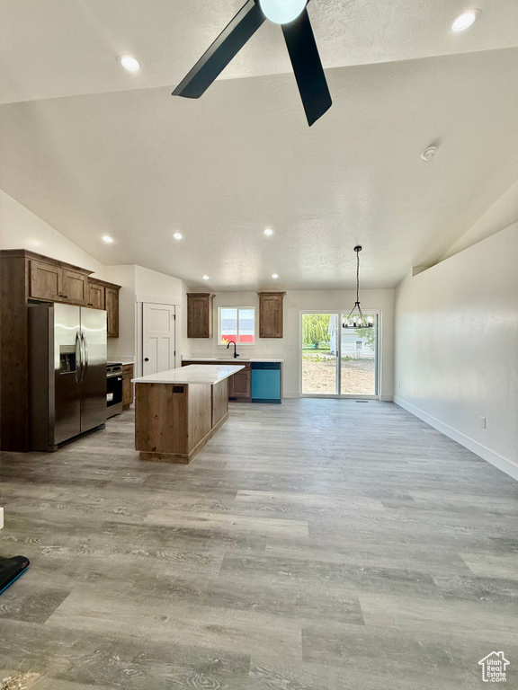 Kitchen with stainless steel refrigerator with ice dispenser, lofted ceiling, ceiling fan, a kitchen island, and open floor plan