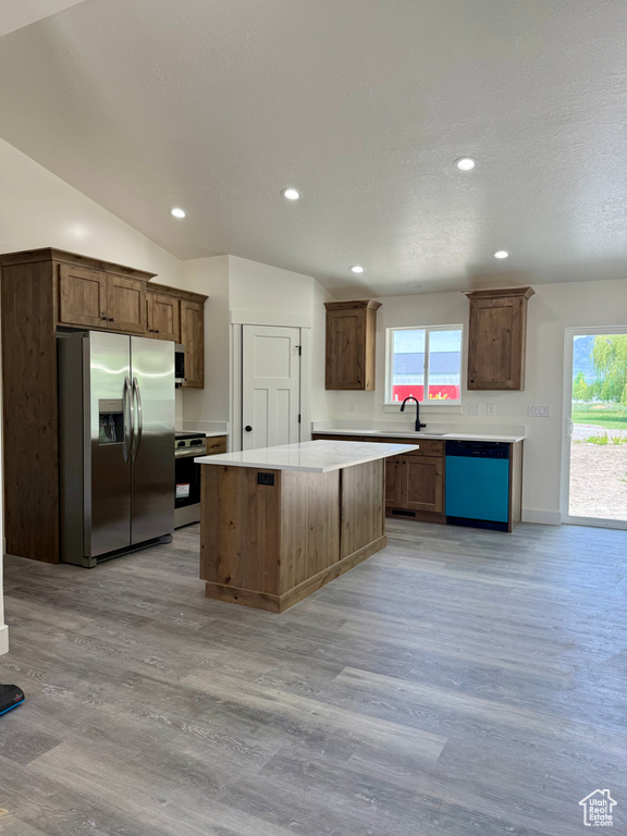 Kitchen with stainless steel appliances, light wood-style floors, a center island, light countertops, and recessed lighting