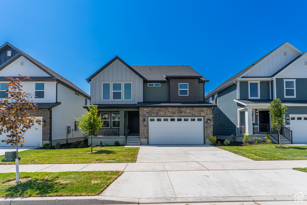 Craftsman house featuring board and batten siding, an attached garage, concrete driveway, and a front lawn