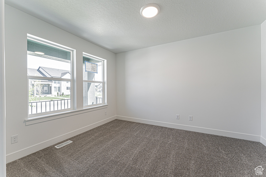 Spare room with dark carpet and a textured ceiling